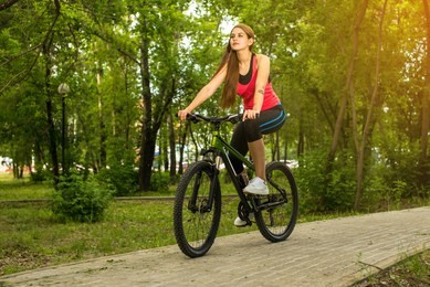 happy girl cyclist riding on a mountain bike outside on the park