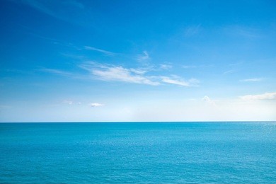 beautiful white clouds on blue sky over calm sea with sunlight reflection, bali indonesia. tranquil sea harmony of calm water surface. sunny sky and calm blue ocean. vibrant sea with clouds on horizon