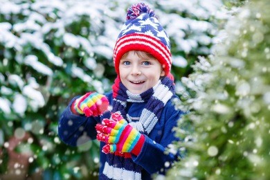 winter portrait of little kid boy in colorful clothes, outdoors during snowfall. active outdoors leisure with children in winter on cold snowy days. happy child having fun with snow
