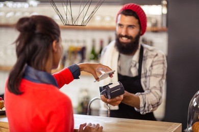 seller taking payment with bank card reader and smartphone in the shop