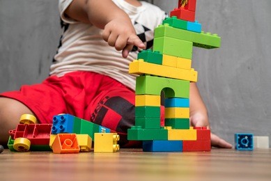 asian kid boy building house from plastic blocks