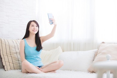 young woman is taking selfies in living room at home, asian