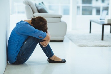 sad woman sitting by wall at home