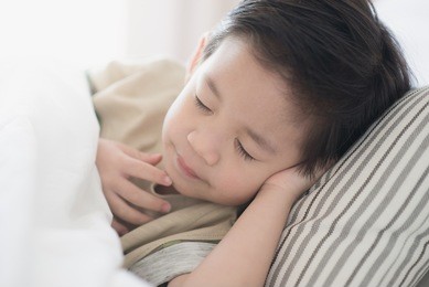 cute asian child lying on white bed