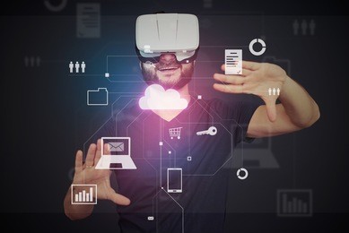 young bearded man in vr-headset is surrounded by virtual data on interactive touch screen over dark background
