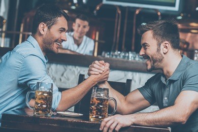 old friends meeting. two cheerful young men drinking beer and having fun in bar