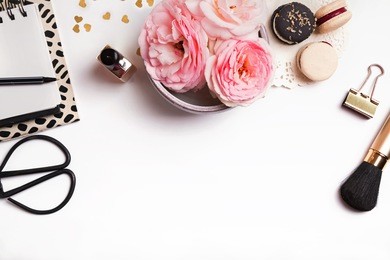 beautiful pink flowers, french macarons, notepad and other cute feminine stuff on white background, top view