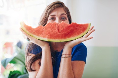 portrait of young woman holding a slice of watermelon in front