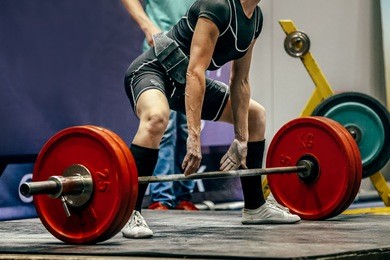 female powerlifter preparing for deadlift of barbell during competition of powerlifting