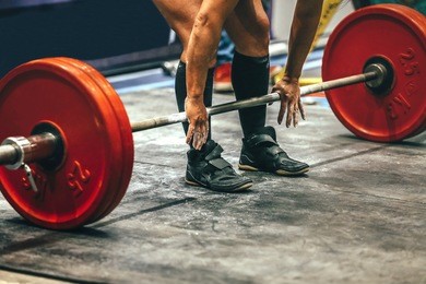 male powerlifter preparing for deadlift of barbell during competition of powerlifting