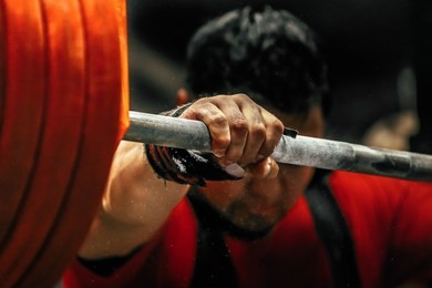 athlete is preparing for a powerlifter squats with a barbell during competition of powerlifting