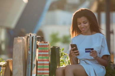woman holding a credit card and using cell phone for online shopping.
