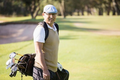 sportsman posing with his golf bag on a field