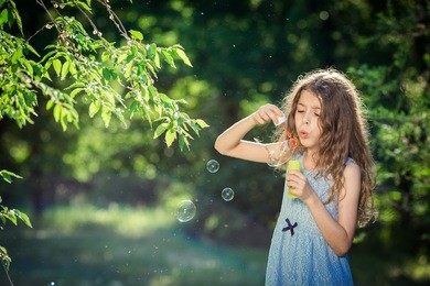 beautiful girl is blowing a bubbles in park
