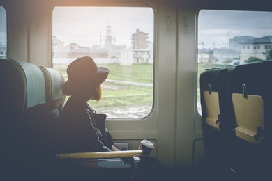 enjoying travel. young pretty woman traveling by the japan classic train from hakata to yufuin japan (limited express yufuin no mori) sitting near the window. vintage filter.