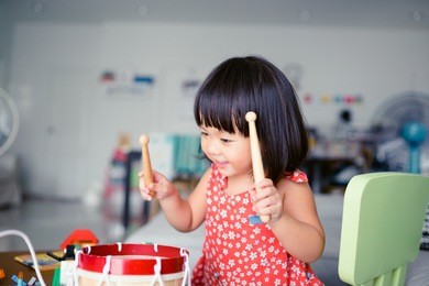 little girl playing drum at home.child development concept.