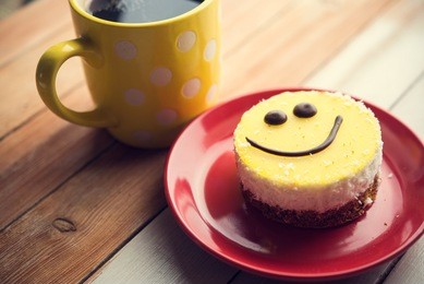 coffee red cup and smile cake on wood table. morning tasty breakfast.
