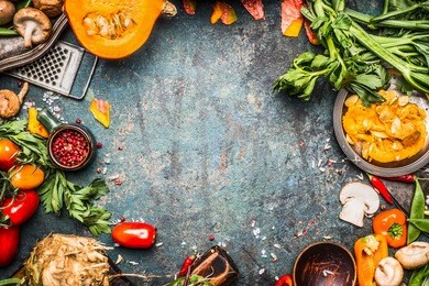 autumn vegetables cooking preparation . pumpkin, tomatoes, root vegetables and mushrooms ingredients on dark rustic background for  thanksgiving day recipes or menu card, top view, frame