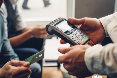 close up of a card payment being made betweem a man and a waiter in a cafe.