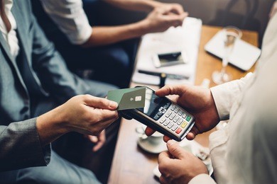 close up of a card payment being made betweem a man and a waiter in a cafe.