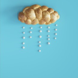 bread in shape of cloud with rain made of meringue on light blue background , wet season concept.