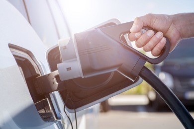 color image of a man's hand preparing to charge an electric car.