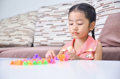 portrait of cute asian little girl playing brick on table at home