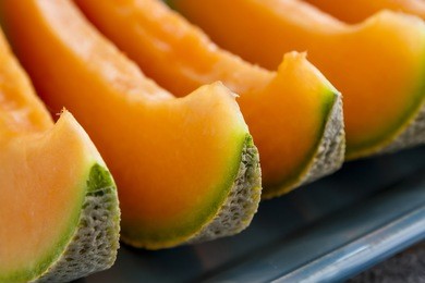 cantaloupe melon slices sitting on blue platter in a row