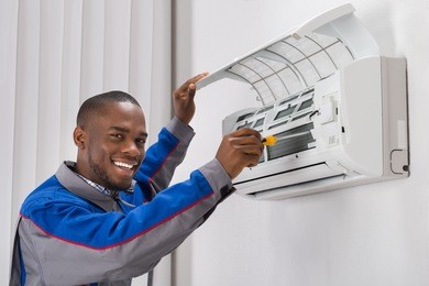 happy young african male technician repairing air conditioner