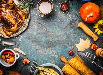 roasted whole chicken or turkey with sauce and grilled autumn vegetables: corn,pumpkin ,paprika on dark rustic background, top view, frame. thanksgiving day food concept