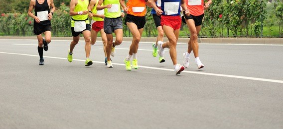 unidentified marathon athletes legs running on city road