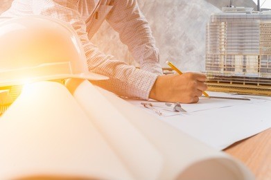 architect working on blueprint. architects workplace - architectural project, blueprints, ruler, helmet and divider. construction concept. engineering tools