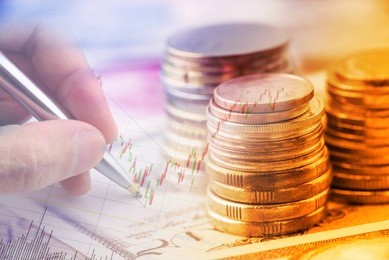 closeup view : stack of coins and a hand holding a ballpoint pen is examining a technical chart of financial instrument. an idea / concept of currency trading, making a decision for an optimal gain.