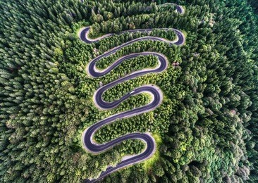 winding road from the high mountain pass in transylvania, romania. great road trip trough the dense woods. aerial view.