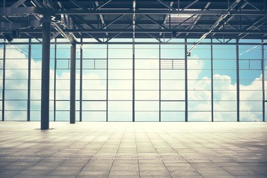 construction, architecture and building concept - airport terminal empty room over blue sky and clouds background