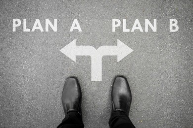businessman in black shoes standing at the crossroad making decision which way to go - plan a or plan b for his business
