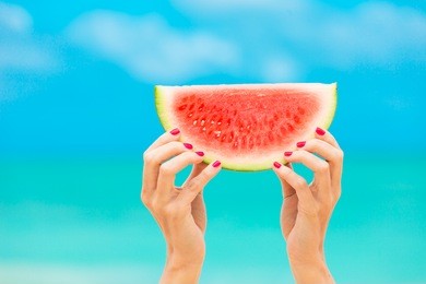 colorful hot summer holidays.  hand holding slice of watermelon on the beach. 