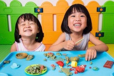 asian little chinese girls playing with colorful clay in indoor playground
