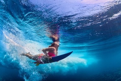 young girl wearing bikini in action - surfer with surf board dive underwater under ocean wave. family lifestyle, people water sport adventure camp and beach extreme swim on summer vacation with child.