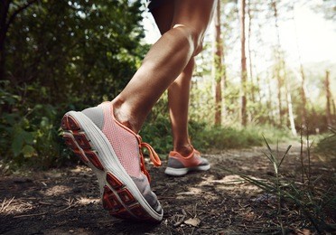 close-up of female hiker feet walking on forest trail. active woman backpacker traveling on the nature. 