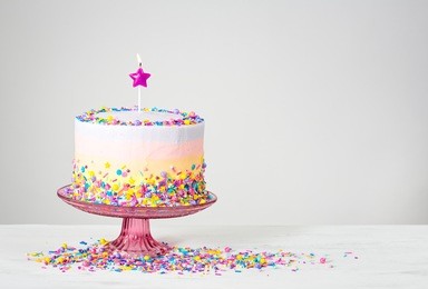 birthday cake with star candle and colorful sprinkles