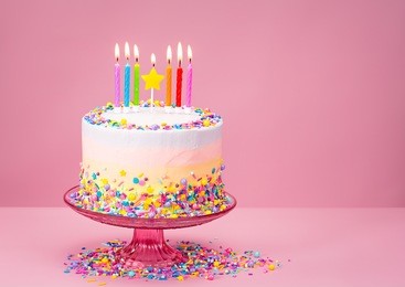 colorful birthday cake with sprinkles over a pink background.