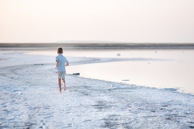 a salt lake shore. a salt lake. a boy runs along the shore of the salt lake