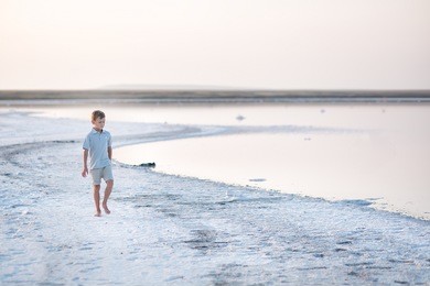 a boy walks along the shore of the lake. a salt lake shore. 
a salt lake. 