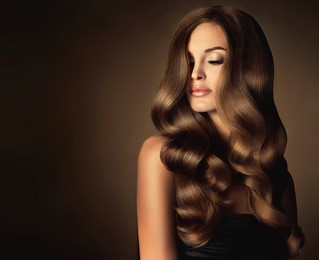 brunette  girl with long  and   shiny wavy hair .  beautiful  model with curly hairstyle . head and shoulders 