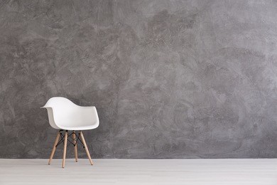 white plastic chair on a background of a gray concrete wall