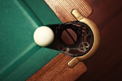 closeup shot of white ball going in billiard pocket