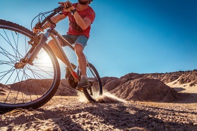 man cycling in the desert with lot of dust