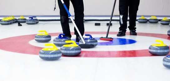 two players with brooms on the ice, determining the strategy during a curling game