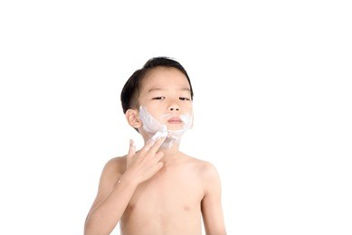 young boy put foam on his face before shaving in the bathroom.